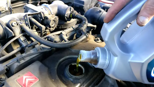 Rellenando aceite de motor por el tapón de llenado de un coche